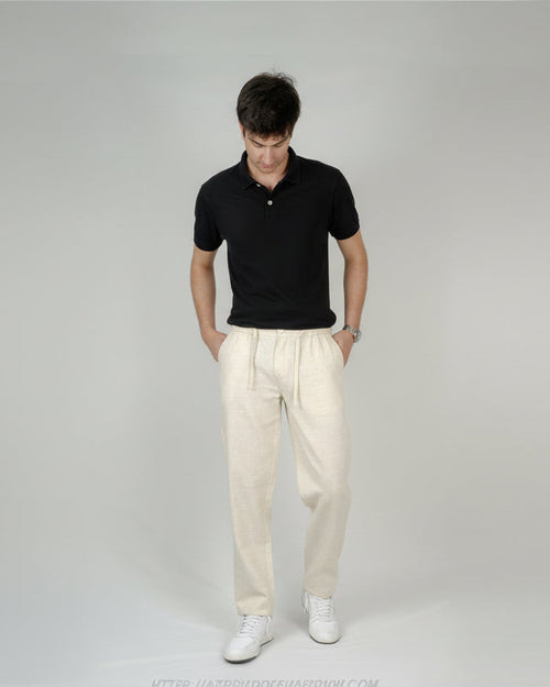 Man wearing a black polo shirt and beige pants on a gray background