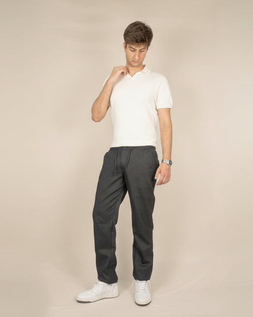 Person wearing a white t-shirt and dark gray pants on a plain background