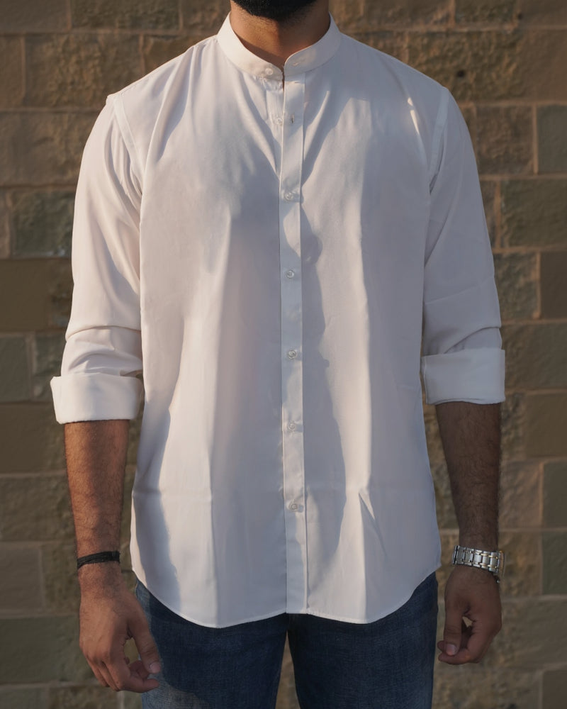 Person wearing a white long-sleeve shirt against a textured wall.