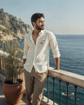 Man standing on a balcony overlooking the ocean with mountains in the background