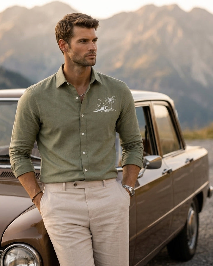 Man standing next to an old car with mountains in the background